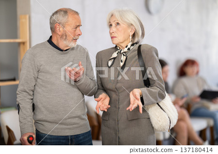 Elderly woman talking to senior man in clinic waiting area Elderly woman talking to senior man in clinic waiting area 137180414