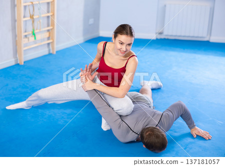 Young woman learns to do painful grip on arm of an attacking man during self defense training Young woman learns to do painful grip on arm of an attacking man during self defense training 137181057