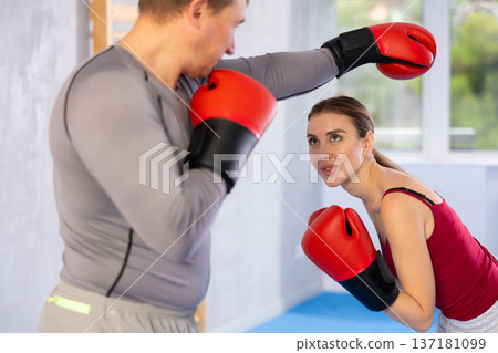 Young girl training boxing kicks on punch mitts held by male instructor Young girl training boxing kicks on punch mitts held by male instructor 137181099
