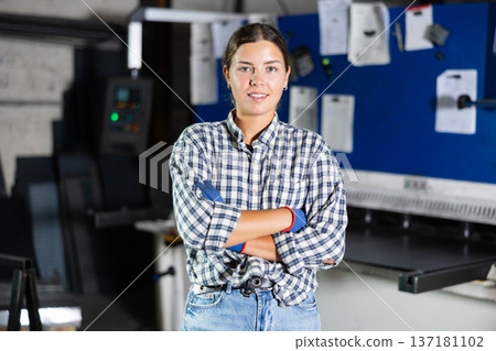 Smiling young female worker posing in metalworking workshop 137181102