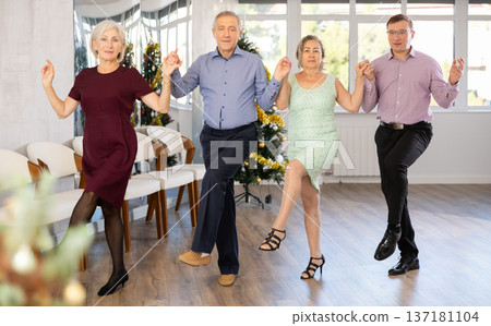 Group of elderly people with middle-aged man perform Irish folk dance during New Year party Group of elderly people with middle-aged man perform Irish folk dance during New Year party 137181104