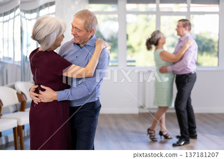 Elderly woman is dancing slow unhurried dance in hugs arms of her senior male partner. Elderly woman is dancing slow unhurried dance in hugs arms of her senior male partner. 137181207
