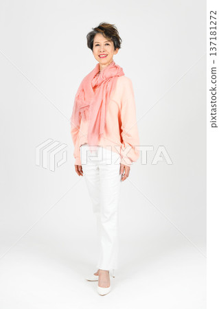 A woman in her 50s standing model-style with her left foot forward on a white background A woman in her 50s standing model-style with her left foot forward on a white background 137181272
