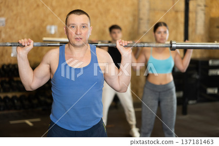 Concentrated athletic man performing exercises with barbell in gym Concentrated athletic man performing exercises with barbell in gym 137181463