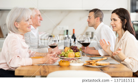 Mother-in-law and daughter-in-law chatting friendly at family dinner Mother-in-law and daughter-in-law chatting friendly at family dinner 137181511