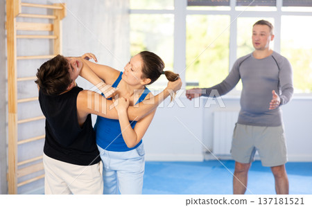 Guy paired up with woman to perform effective impact on pain points while learning self-defense. 137181521