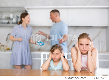 Distraught teenage girls suffering from parents conflict sitting in kitchen 137181523