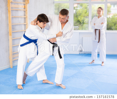 Male athletes in pair conduct training battle in oriental fighting technique under guidance of coach 137181578