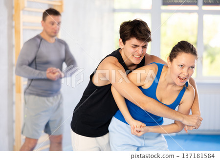Guy and woman train to perform defense of strangling opponent, while learning self-defense 137181584
