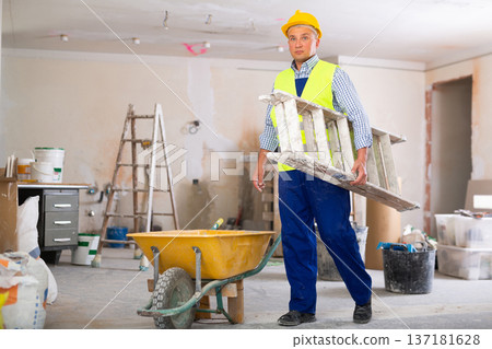 Man builder carrying stepladder Man builder carrying stepladder 137181628