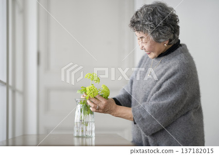 Senior woman decorating her room with flowers Senior woman decorating her room with flowers 137182015