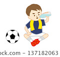 A soccer boy sitting on the ground with a towel around his neck to hydrate 137182063