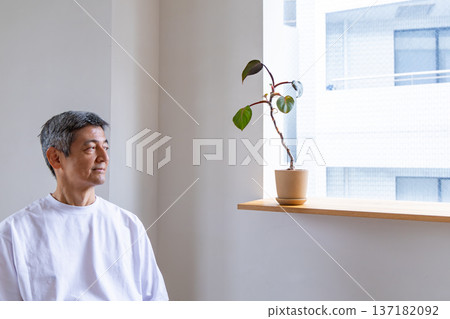Senior man looking out the window from the living room Senior man looking out the window from the living room 137182092