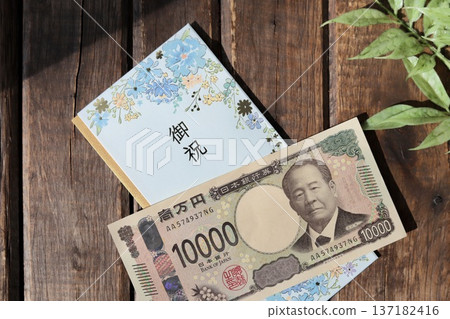 A light blue, floral gift envelope and a new 10,000 yen bill. A gift for graduation or graduation celebration. 137182416
