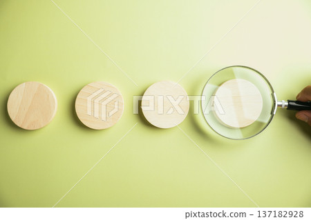 Magnifying glass over wooden circle on green background. Concept: search, focus, detail. Magnifying glass over wooden circle on green background. Concept: search, focus, detail. 137182928