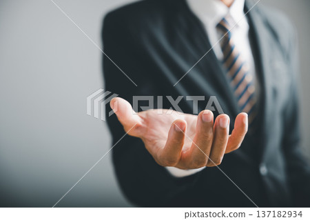 Closeup of a businessman's open hand, fingers extended, against a blurred background of his suit and tie. Closeup of a businessman's open hand, fingers extended, against a blurred background of his suit and tie. 137182934
