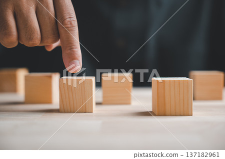 A hand points at a wooden block in a row of blocks.  Concept for choice, decision, or opportunity. 137182961