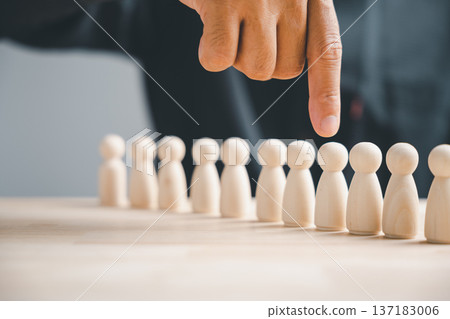 Finger pointing at one of a row of wooden figures. Concept of choosing the best candidate. 137183006