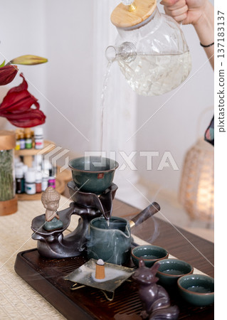 Tea pouring. Hot drink. Woman hands filling glass teapot with refreshing liquid healthy lifestyle burning incense. Tea pouring. Hot drink. Woman hands filling glass teapot with refreshing liquid healthy lifestyle burning incense. 137183137