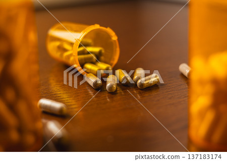 Pill bottles and capsules on wooden table during a health care routine Pill bottles and capsules on wooden table during a health care routine 137183174