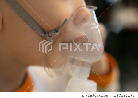 Child using a breathing mask at home for health support during treatment 137183175