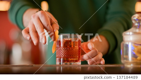 Preparing drink. Citrus cocktail. Bartender rubbing orange peel juice wiping rim of wide glass. Aromatic refreshing ice beverage recipe. Preparing drink. Citrus cocktail. Bartender rubbing orange peel juice wiping rim of wide glass. Aromatic refreshing ice beverage recipe. 137184489