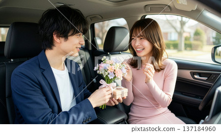 一名男子在車上向一名女子贈送白色情人節禮物。 137184960