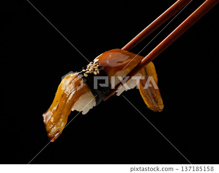 黑色背景上的用筷子夾著的康吉鰻壽司 黑色背景上的用筷子夾著的康吉鰻壽司 137185158