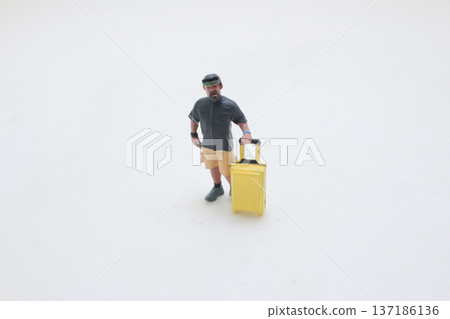 Miniature Traveler Pulls Bright Yellow Suitcase Across Surface Miniature Traveler Pulls Bright Yellow Suitcase Across Surface 137186136