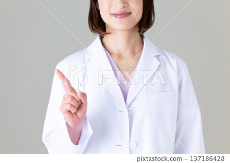 一位身穿白大褂的中年女醫生舉起她的食指 137186428