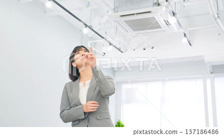 Female business person looking at the office ceiling Female business person looking at the office ceiling 137186486