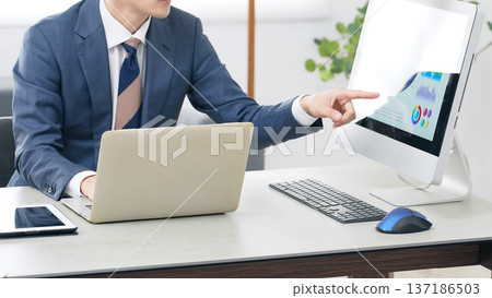A male business person working while looking at a PC in the office A male business person working while looking at a PC in the office 137186503