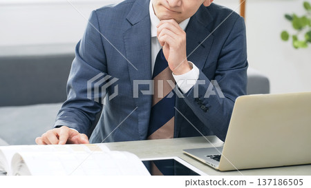 A male business person worried while working in the office A male business person worried while working in the office 137186505