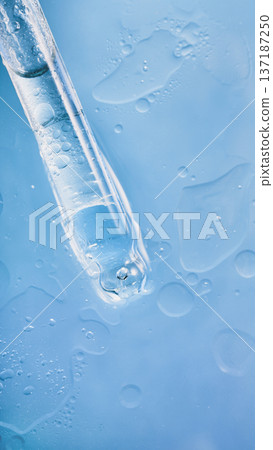 Dropper with drop of transparent liquid creating bubbles on light blue surface Dropper with drop of transparent liquid creating bubbles on light blue surface 137187250