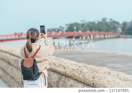 Woman tourist taking photo Fukuura jima bridge or the bridge of romantic encounters for Fukuura Island at Matsushima Bay in Matsushima, Miyagi Prefecture, Tohoku, Japan. Landmark and famous Vacation Woman tourist taking photo Fukuura jima bridge or the bridge of romantic encounters for Fukuura Island at Matsushima Bay in Matsushima, Miyagi Prefecture, Tohoku, Japan. Landmark and famous Vacation 137187985