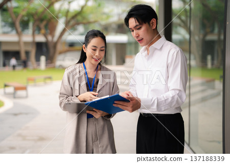 Business team walked and talked outside the office building, discussing a business project with partners, demonstrating teamwork. Business team walked and talked outside the office building, discussing a business project with partners, demonstrating teamwork. 137188339
