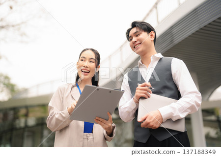 Business team walked and talked outside the office building, discussing a business project with partners, demonstrating teamwork. Business team walked and talked outside the office building, discussing a business project with partners, demonstrating teamwork. 137188349