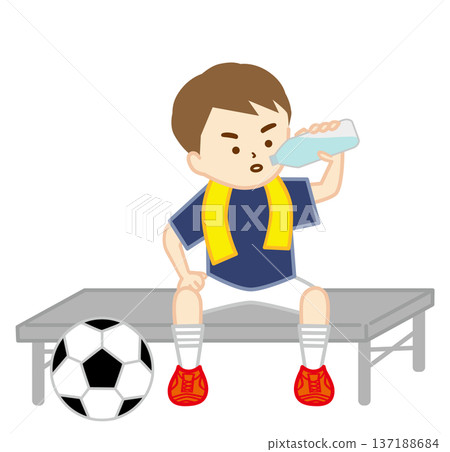 一個踢足球的男孩坐在長椅上，脖子上搭著毛巾，正在補充水分。 137188684