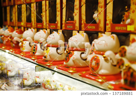 Collection of decorative ceramic lucky cat figurines displayed on shelves, showcasing vibrant colors and intricate designs, symbolizing prosperity and good fortune in various cultures Collection of decorative ceramic lucky cat figurines displayed on shelves, showcasing vibrant colors and intricate designs, symbolizing prosperity and good fortune in various cultures 137189881