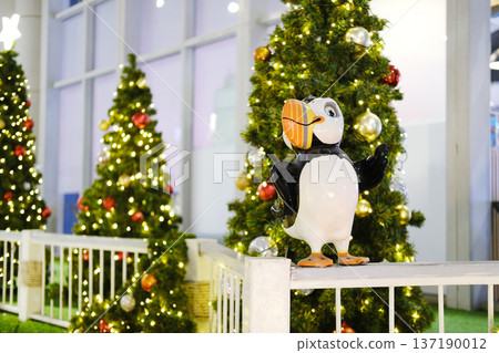 Festive decor featuring a whimsical bird statue surrounded by beautifully adorned Christmas trees, creating a joyful atmosphere in a public space for holiday celebrations Festive decor featuring a whimsical bird statue surrounded by beautifully adorned Christmas trees, creating a joyful atmosphere in a public space for holiday celebrations 137190012