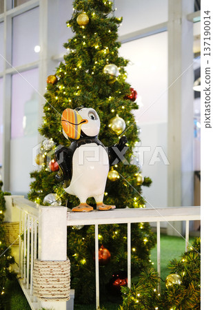 Festive Christmas decor featuring a whimsical bird sculpture beside a beautifully adorned tree, creating a joyful atmosphere in a public space with twinkling lights and vibrant ornaments Festive Christmas decor featuring a whimsical bird sculpture beside a beautifully adorned tree, creating a joyful atmosphere in a public space with twinkling lights and vibrant ornaments 137190014