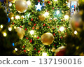 Festive Christmas tree adorned with golden and red ornaments, twinkling lights, and a star on top, creating a warm holiday atmosphere and joyful ambiance 137190016