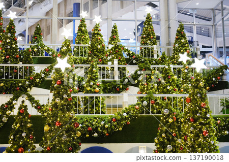 Festively decorated Christmas trees adorned with colorful ornaments and bright stars create a joyful atmosphere in a public space, enhancing the holiday spirit and inviting celebration Festively decorated Christmas trees adorned with colorful ornaments and bright stars create a joyful atmosphere in a public space, enhancing the holiday spirit and inviting celebration 137190018
