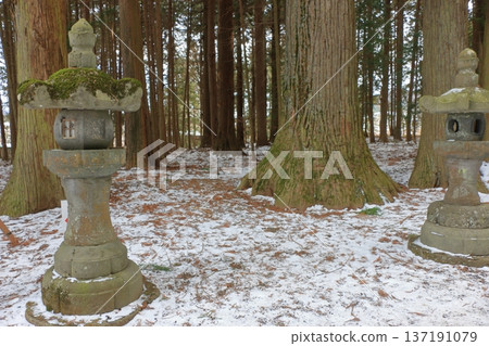 The long pathway to the Kitaguchi Hongu Sengen Jinja shrine, the entrance to the path to climb Mt. Fuji, lined with stone lanterns in Fujiyoshida in Yamanashi Japan on a snow covered winter day. The long pathway to the Kitaguchi Hongu Sengen Jinja shrine, the entrance to the path to climb Mt. Fuji, lined with stone lanterns in Fujiyoshida in Yamanashi Japan on a snow covered winter day. 137191079