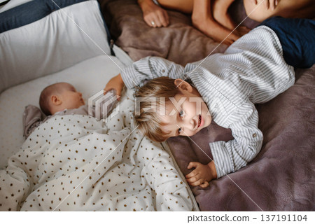 Toddler Touching Newborn Hand Beside Bassinet Toddler Touching Newborn Hand Beside Bassinet 137191104