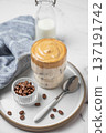 Dalgona coffee. Whipped instant iced coffee in a glass on a plate with coffee beans and spoon 137191742