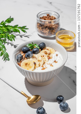 Greek yogurt with granola, blueberry and banana in a bowl on a marble background Greek yogurt with granola, blueberry and banana in a bowl on a marble background 137191762