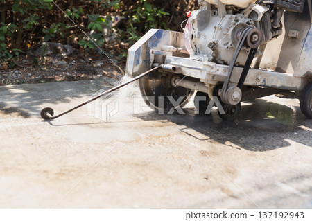 Close up of a concrete floor saw cutting through pavement with water cooling system. Close up of a concrete floor saw cutting through pavement with water cooling system. 137192943