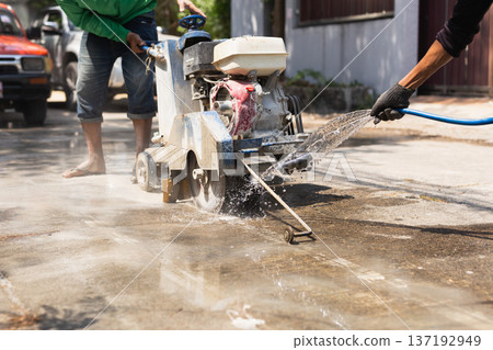 Road worker cutting concrete with a gasoline powered saw during road repair maintenance. Road worker cutting concrete with a gasoline powered saw during road repair maintenance. 137192949