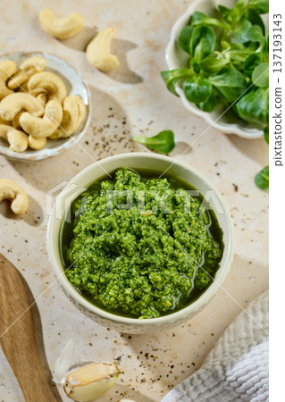 Fresh homemade green sprout pesto in bowl on sunny kitchen table with ingredients 137193143